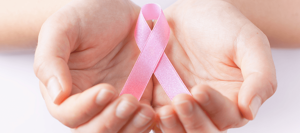 Mão segurando laço rosa em representatividade ao outubro rosa